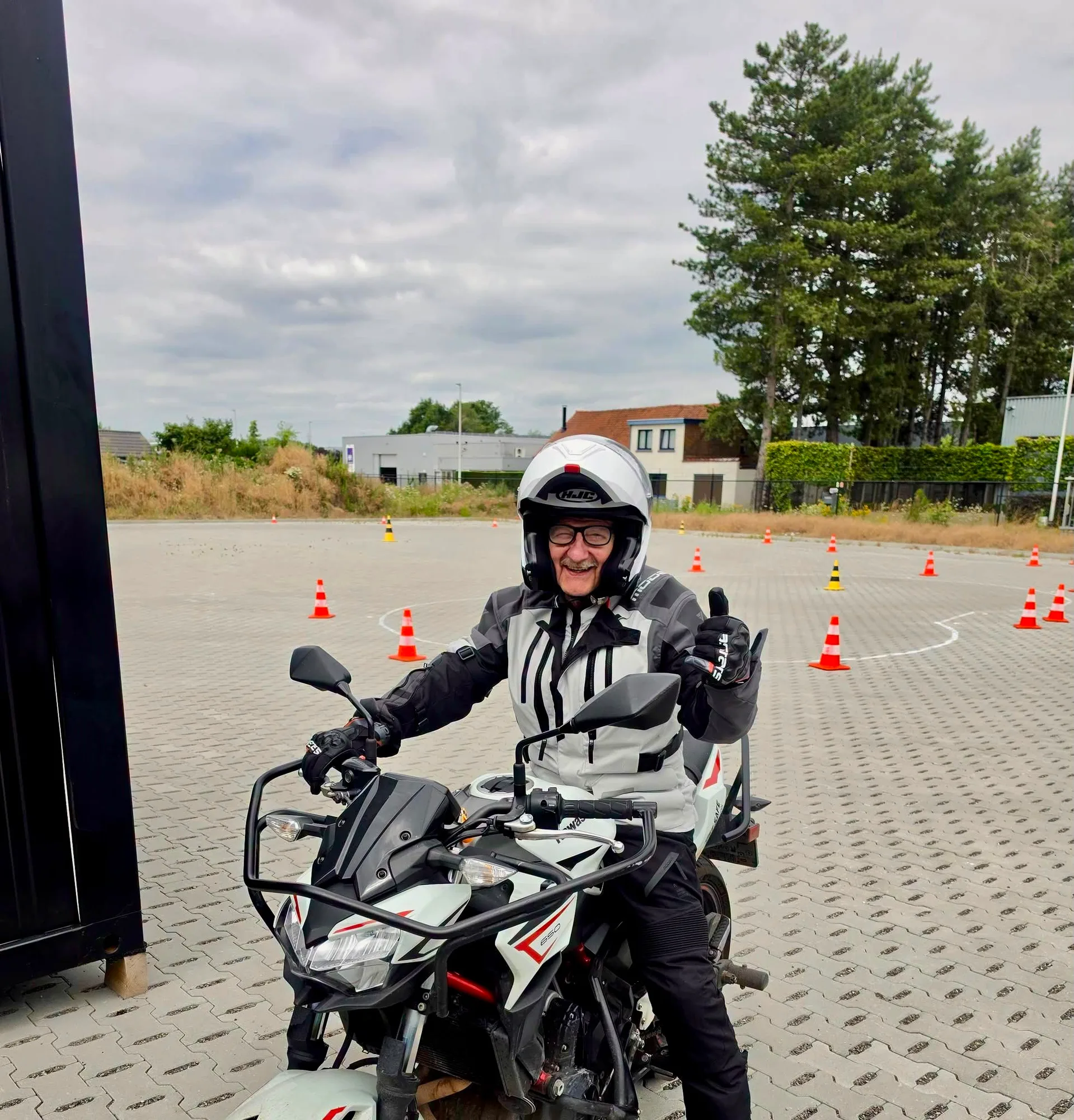 Leerling op zijn motor geeft lachend duim omhoog na de rijles
