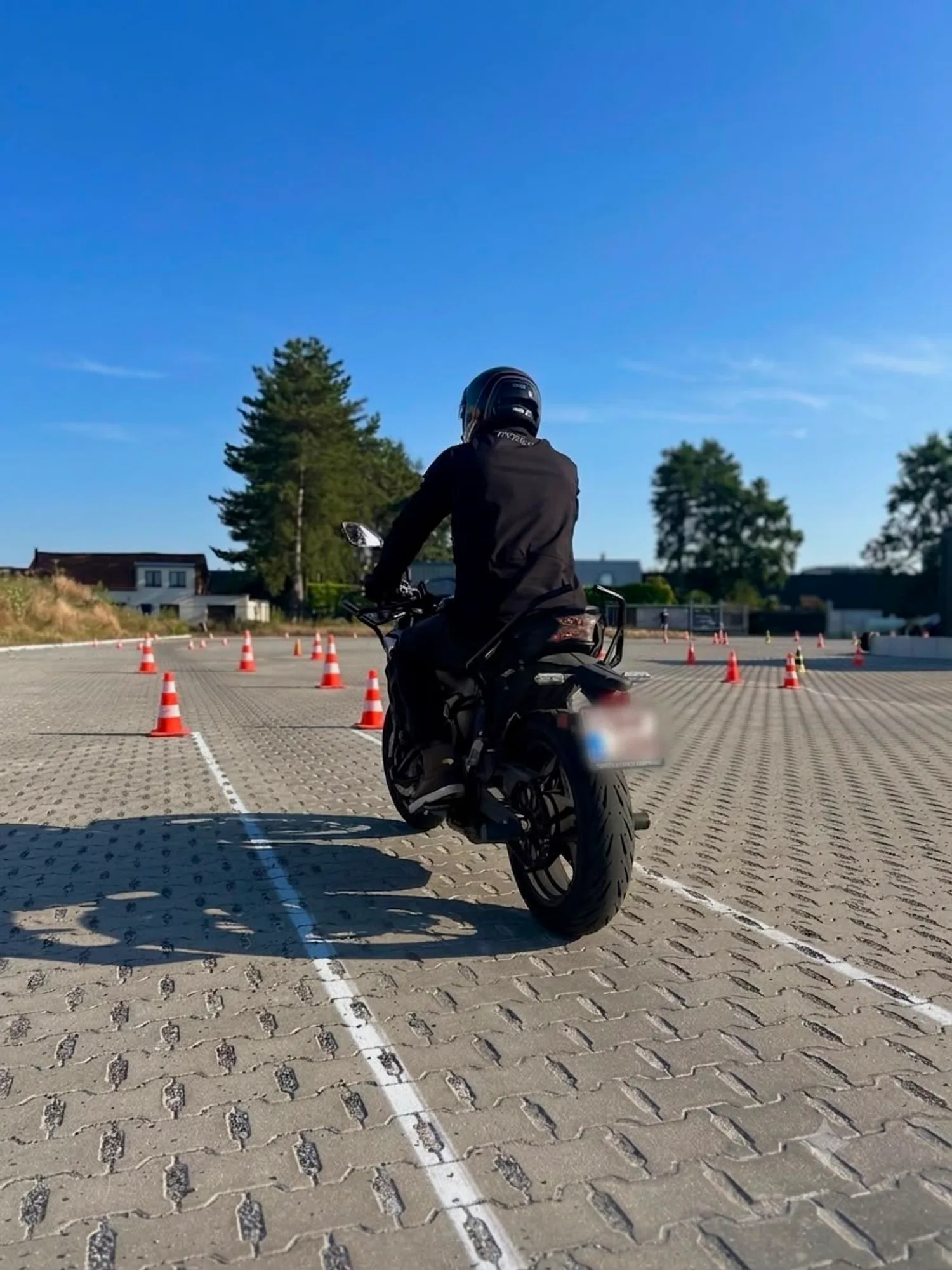 Motorrijder in lesuitrusting oefent tussen pylonen op het oefenterrein